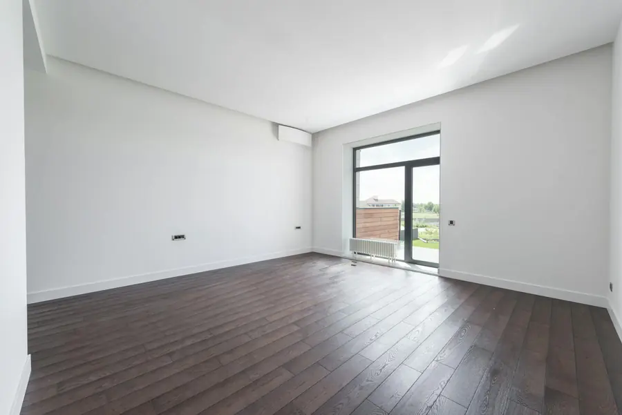 Heller, leerer Raum mit Parkettboden nach besenreiner Wohnungsauflösung